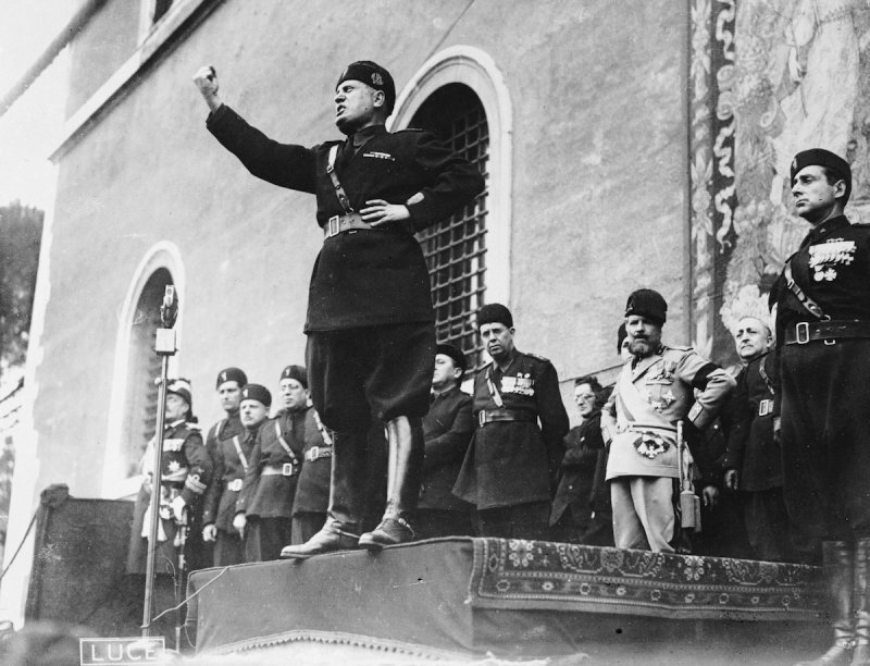 Black and white photo of Mussolini giving a speech with fist raised