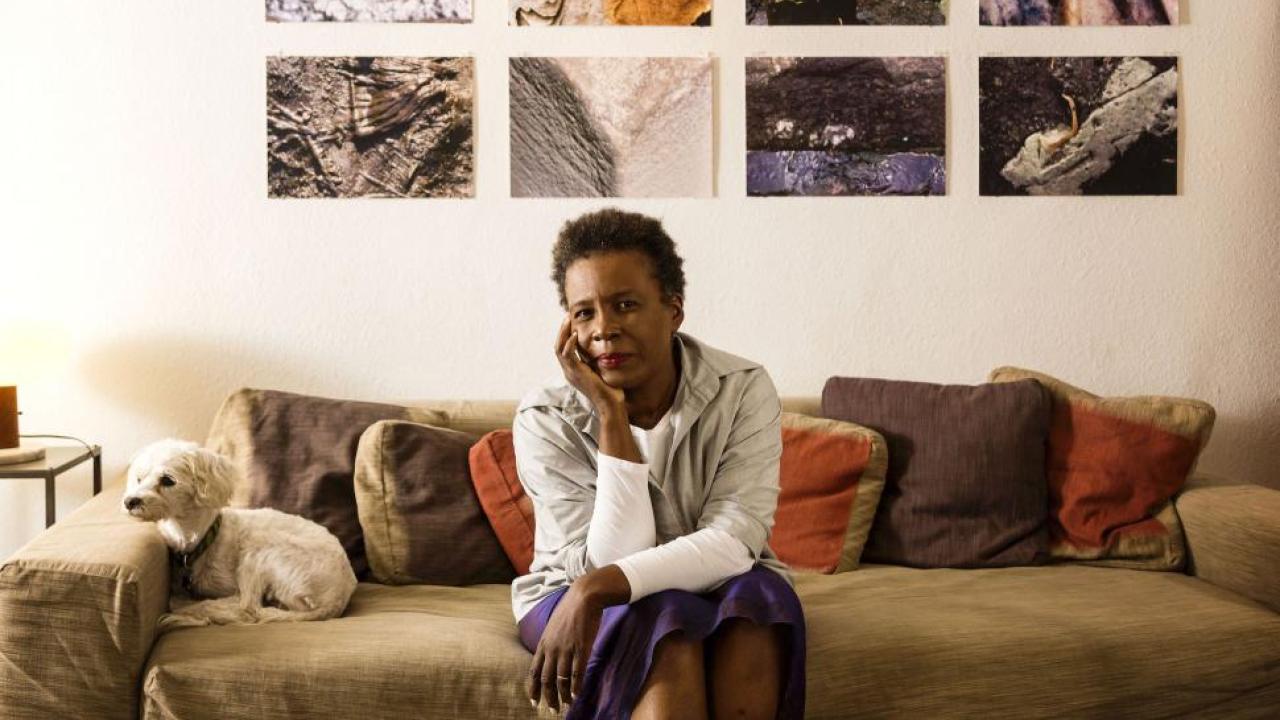 Portrait of Claudia Rankine sitting on couch with her dog