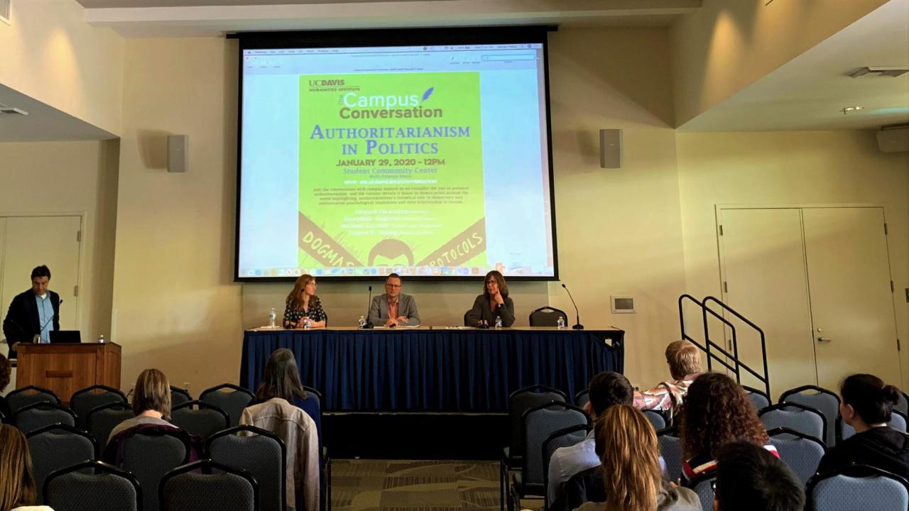 Panel of faculty members sitting at a table under poster reading "Authoritarianism in Politics"