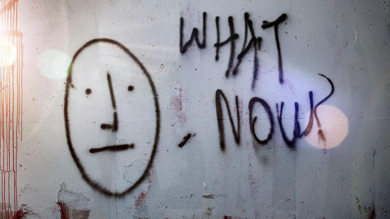 Image by Tim Mossholder on Unsplash Spray-painted graffiti of a face with blank expression and the words "What now?"