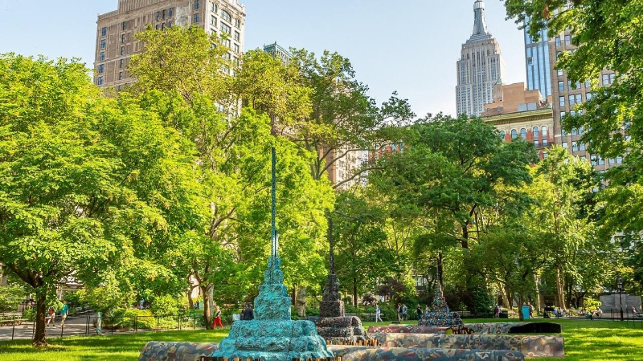 multicolored sculpture in an NYC park with empire state building in the background