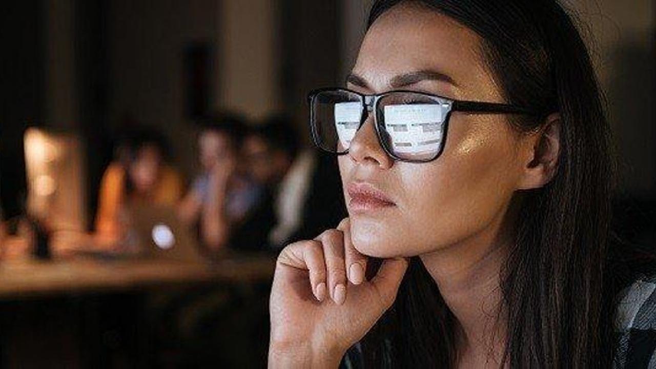 Person working at computer with screen reflected in their glasses