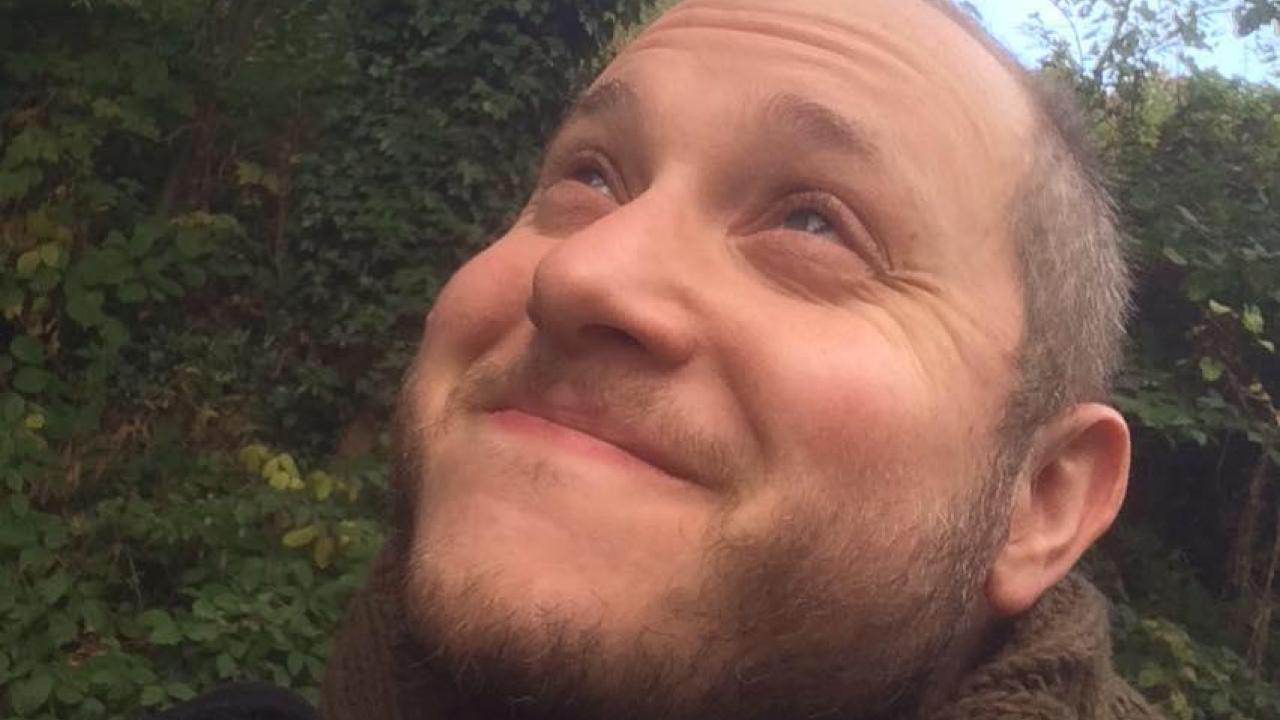 Image of Ben Spatz. Image description: a white person standing outside smiles and looks into the upper left distance.