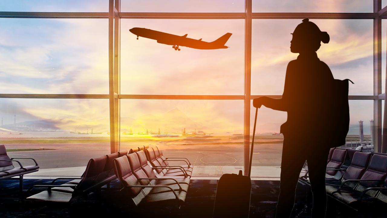 Person looking out an airport window at sunset