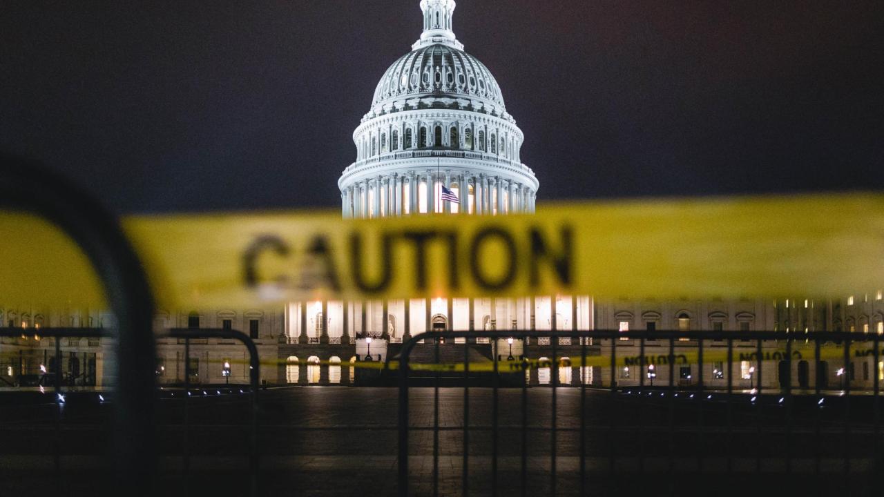 The US Capitol at night, with yellow CAUTION tape in the foreground.