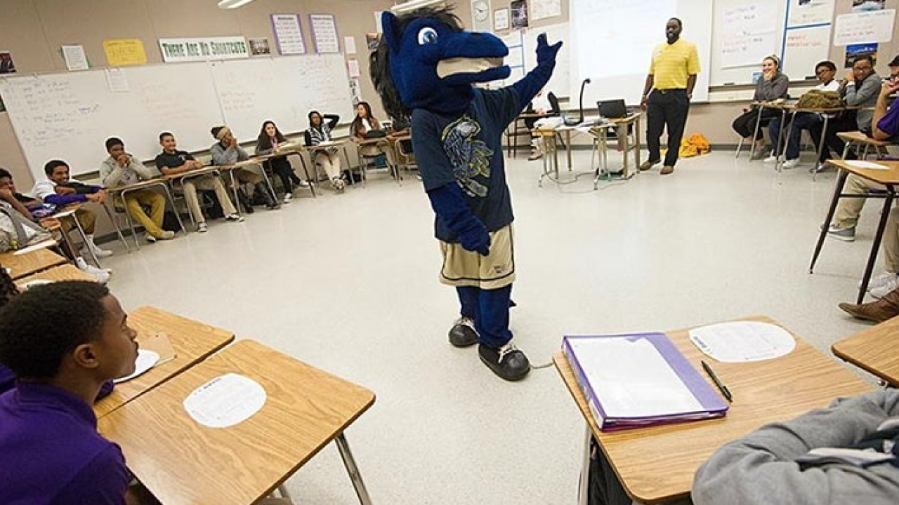Gunrock mascot stands in the middle of a classroom surrounded by teenagers seated at desks