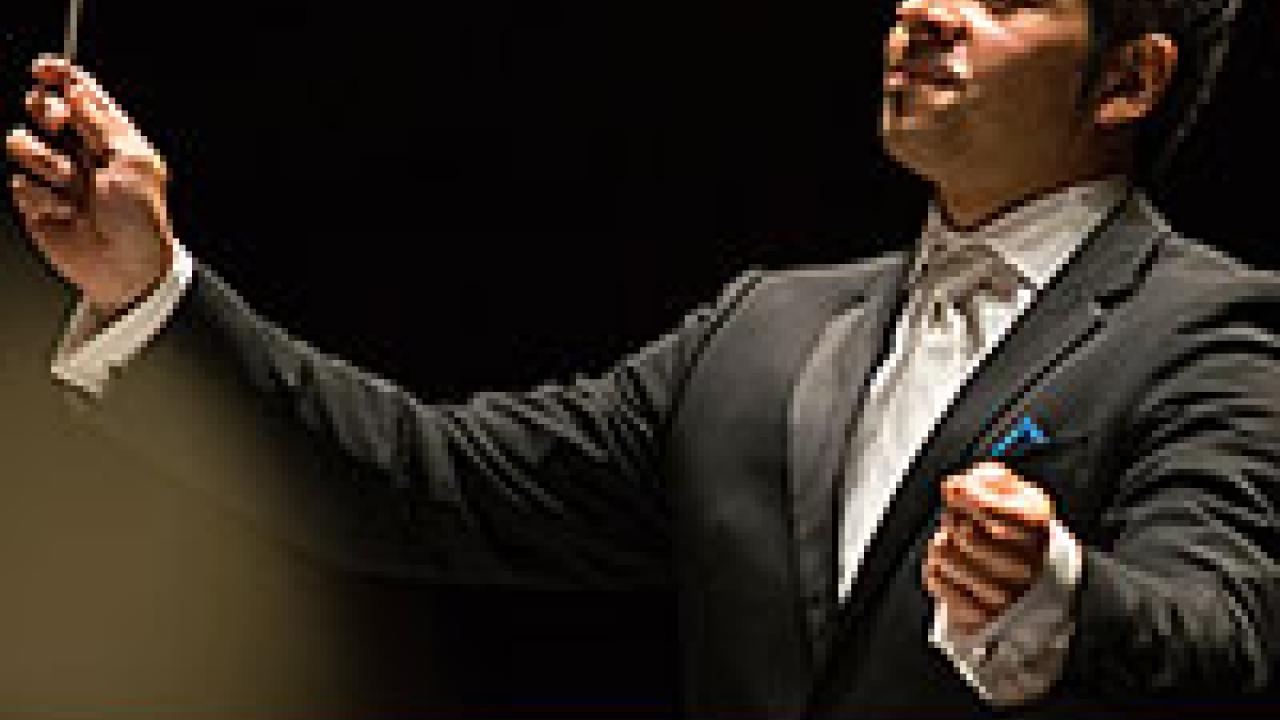 A photo of a conductor in black tie with the words "At Pitzer" at the bottom
