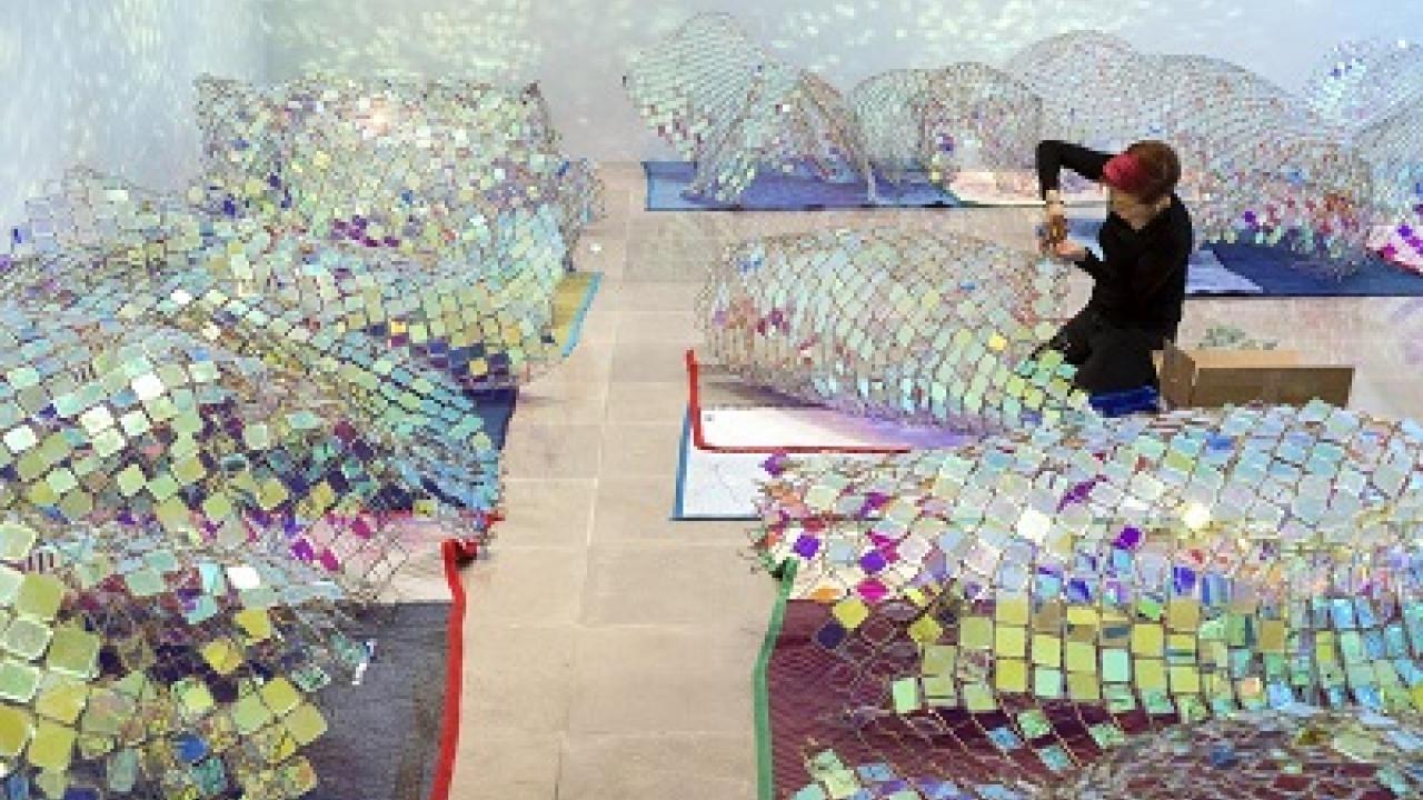 The artist Soo Sunny Park surrounded by multicolored sculptures made of light-refracting squares of glass