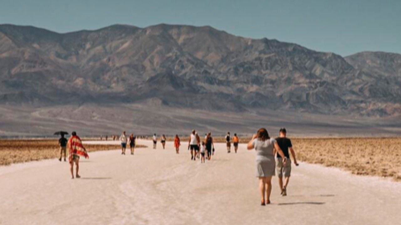 People walking along wide dry road towards mountains