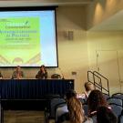 Panel of faculty members sitting at a table under poster reading "Authoritarianism in Politics"