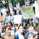 Protesters with signs. One sign reads "Save The Planet" in green.